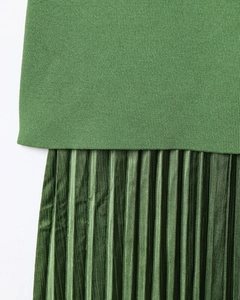 Détail de la maille et du tissu plissé vert foncé de cette robe élégante chic