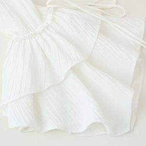 Elegant white chiffon blouse featuring layered ruffle details and vertical pleated texture