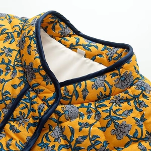 Detailed macro view of yellow floral quilted jacket with navy trim and stand-up collar