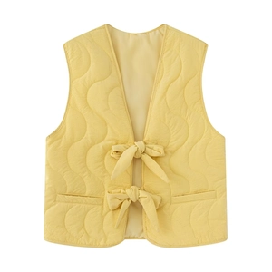 Detail view of yellow quilted vest with wave pattern stitching and bow tie closures