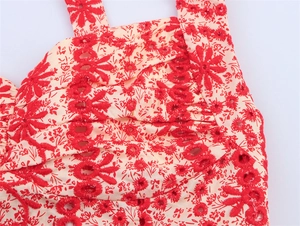 Detail of red floral embroidery and delicate eyelet design on beige halter neck top