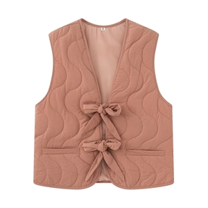 Detail of pink-brown quilted vest with wave pattern and delicate ribbon bow ties
