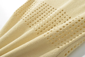 Vue macro détaillée du tissu en maille jaune pâle respirant avec des motifs ajourés ronds