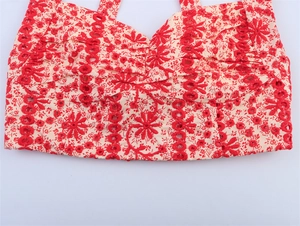 Detailed embroidery of red floral patterns on a white eyelet crop top for women