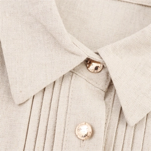 Detailed view of beige linen dress collar with pintucks and gold metal buttons