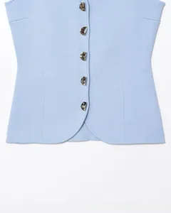 Dettaglio del gilet in maglia azzurra con particolari bottoni in metallo argento ondulati