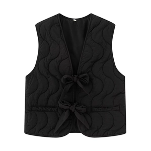 Detailed view of wave quilted black vest featuring front tie-up bows and a sleek V-neckline