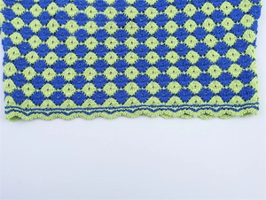 Detailed macro view of the blue-green diamond knit fabric and scalloped hemline