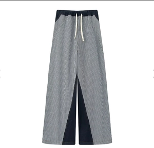 Detailed view of striped wide-leg trousers featuring contrasting navy blue panels and drawstring