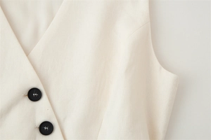 Close-up of cream V-neck vest with textured knit fabric and matte black buttons