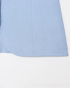 Dettaglio dell'orlo del gilet in maglia azzurro con cuciture fini e trama morbida