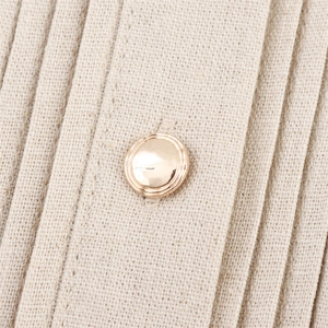 Detailed close-up of a beige pleated fabric featuring a central gold button accent