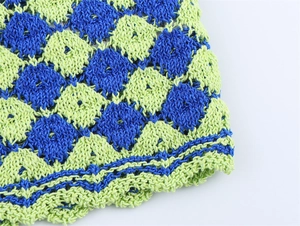 Detailed close-up of blue and green hand-crocheted argyle pattern with wavy hem edges