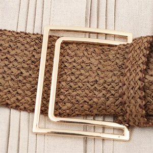 Detail of coffee brown woven belt with a square gold alloy buckle on beige fabric