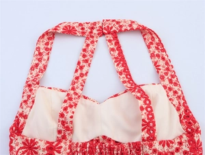 Detail of red floral embroidery on beige halter top with cross straps and elastic smocked back