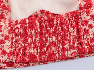 Detailed macro shot of red floral smocking and delicate hollow embroidery on the waist