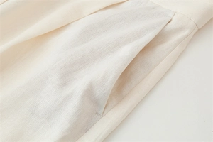 Detailed close-up of cream cotton-linen fabric showing texture and slanted pocket design