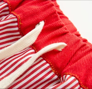 Detail of red and white striped wide-leg pants featuring elastic waist and drawstrings