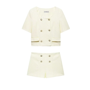 Dettaglio di un completo due pezzi in tweed crema con top a maniche corte e shorts con bottoni d'oro
