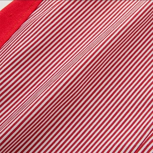 Detailed macro view of red and white striped fabric texture with solid red stitching