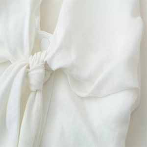 Detailed close-up of white halter top featuring a knotted tie design and fabric button
