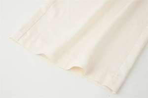 Detailed macro view of the cream cotton-linen blend fabric texture on the sleeveless suit