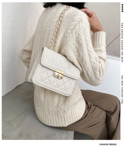 White quilted flap bag with gold chain strap shown on model's shoulder for size perspective