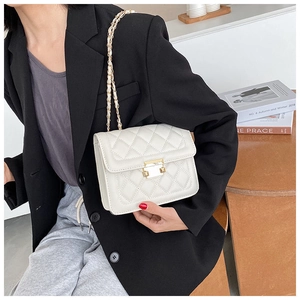 Detailed view of a white quilted crossbody bag with gold chain and metal lock on a model