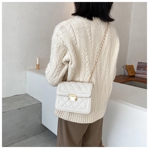 Close-up of white quilted crossbody bag with gold chain strap and metal clasp on model