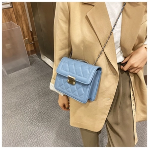 Close-up of light blue quilted crossbody bag featuring a gold chain and square metal lock