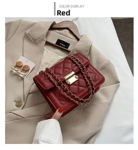 Detail of red quilted chain crossbody bag with golden twist lock and luxury texture
