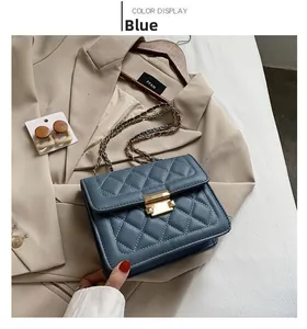 Detail of blue quilted chain bag with gold metal clasp on aesthetic clothing backdrop