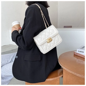 Detail of white quilted crossbody bag with golden rectangular lock and chain strap