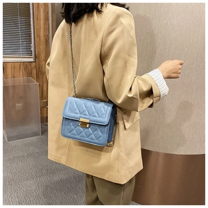 Blue quilted leather crossbody bag with gold chain strap shown on model in street style
