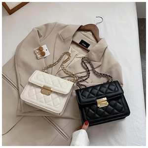 Close-up of quilted flap crossbody bags with gold locks and chain straps on beige blazer