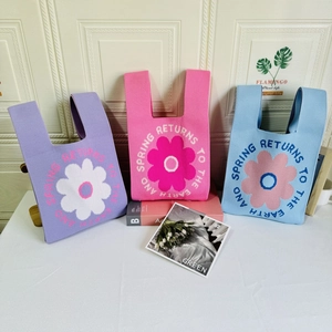 Detailed knit texture of floral tote bags in lavender, pink and blue with woven slogans