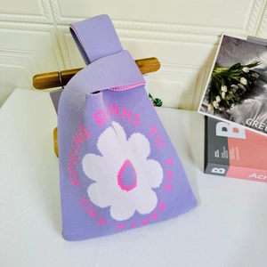 Detailed close-up of purple knit tote bag with white floral pattern and spring text