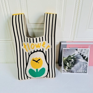 Close-up of knit tote bag featuring black stripes and a yellow flower pattern