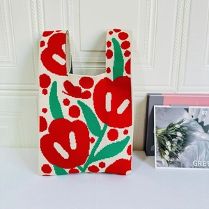 Close-up of knit tote bag with large red tulip pattern on white textured background