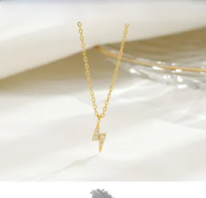Close-up of golden lightning bolt pendant with five white crystals on a dainty chain