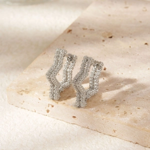 Elegant silver star-shaped hoop earrings with textured finish on a stone display