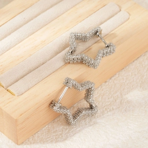 Elegant silver star-shaped hoop earrings with a sparkling textured finish on a jewelry stand