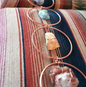 Detail of handmade metal rings with wire-wrapped raw gemstones in blue, yellow and red