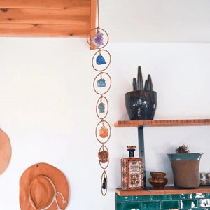 Detailed wall hanging featuring seven raw chakra gemstones in vertical brass rings