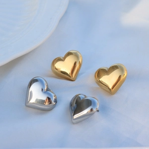 Detailed view of puffy heart stud earrings in polished gold and silver finishes