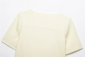 Dettaglio della trama del tessuto in tweed e dello scollo sul top a maniche corte giallo