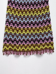 Detail of colorful zigzag knit fabric with boho tassel hem and crochet openwork texture