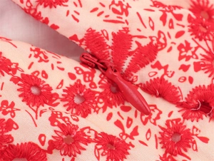 Macro shot of red floral embroidery lace and matching hidden zipper on a beige skirt