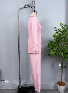 Detailed view of pink suit jacket featuring decorative feather cuffs and straight trousers