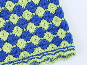 Macro view of green and blue checkered knit fabric with wavy scalloped edge detail